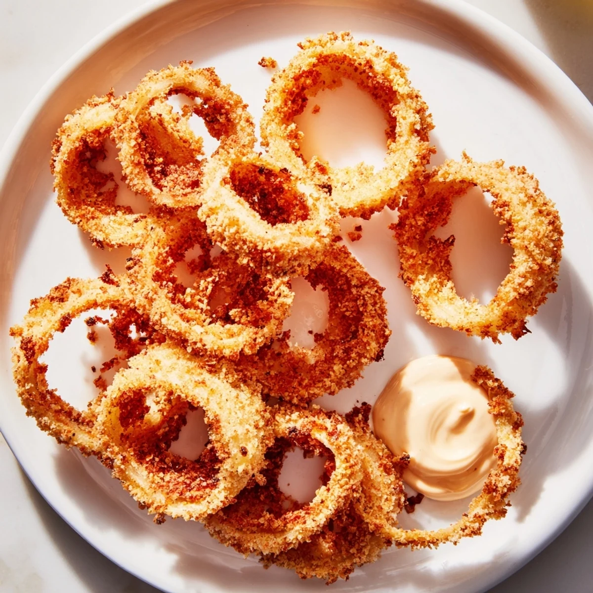 Crispy Air Fryer Onion Rings with Dip served on a white plate, golden brown with a creamy sauce.  