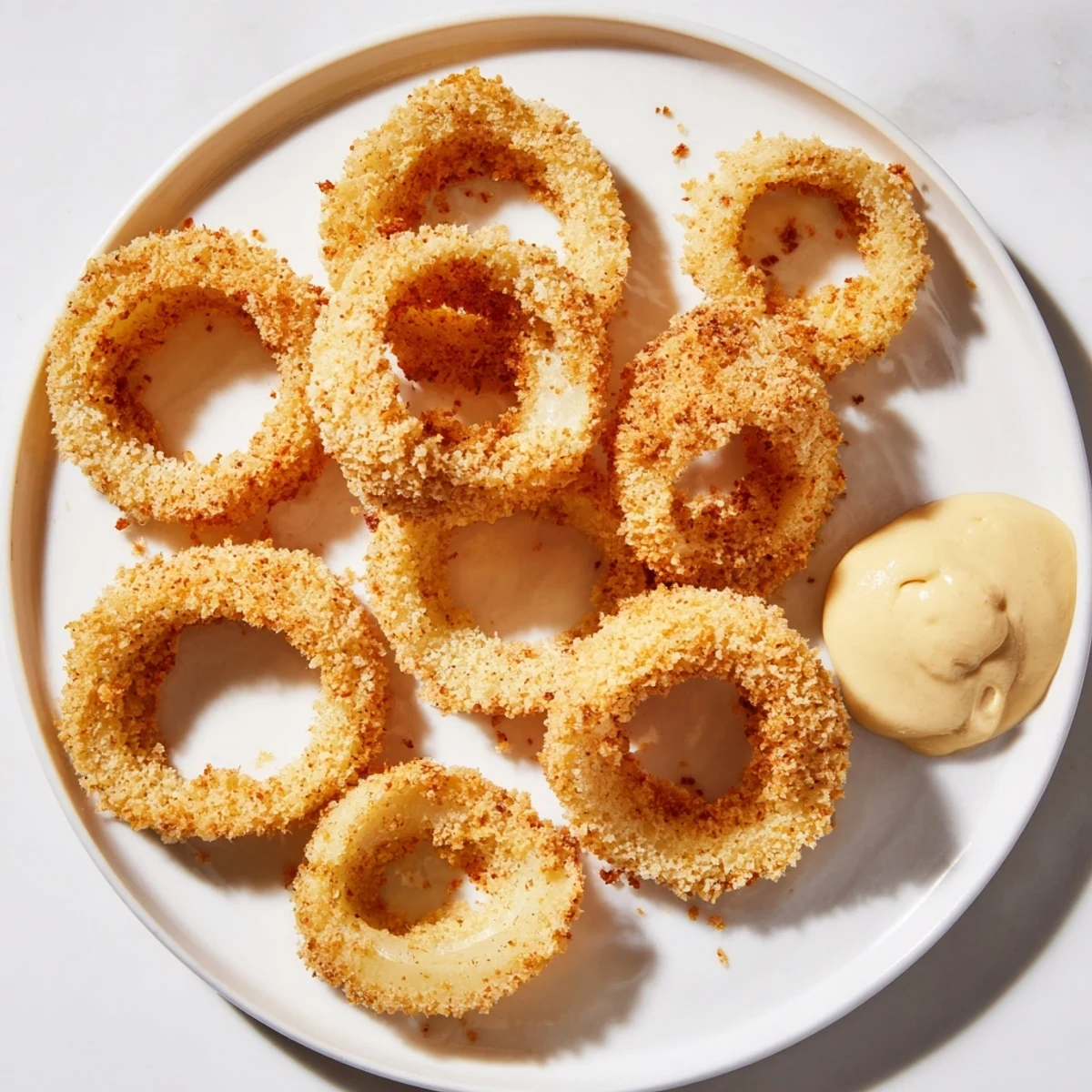 A close-up of Crispy Air Fryer Onion Rings with Dip, showing crunchy panko texture and tangy sauce.  