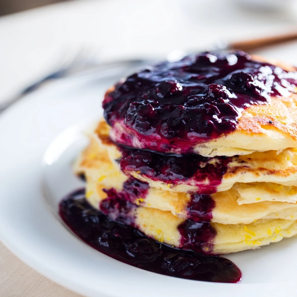 Warm Lemon Ricotta Pancakes with Blueberry Syrup are served fresh from the griddle.