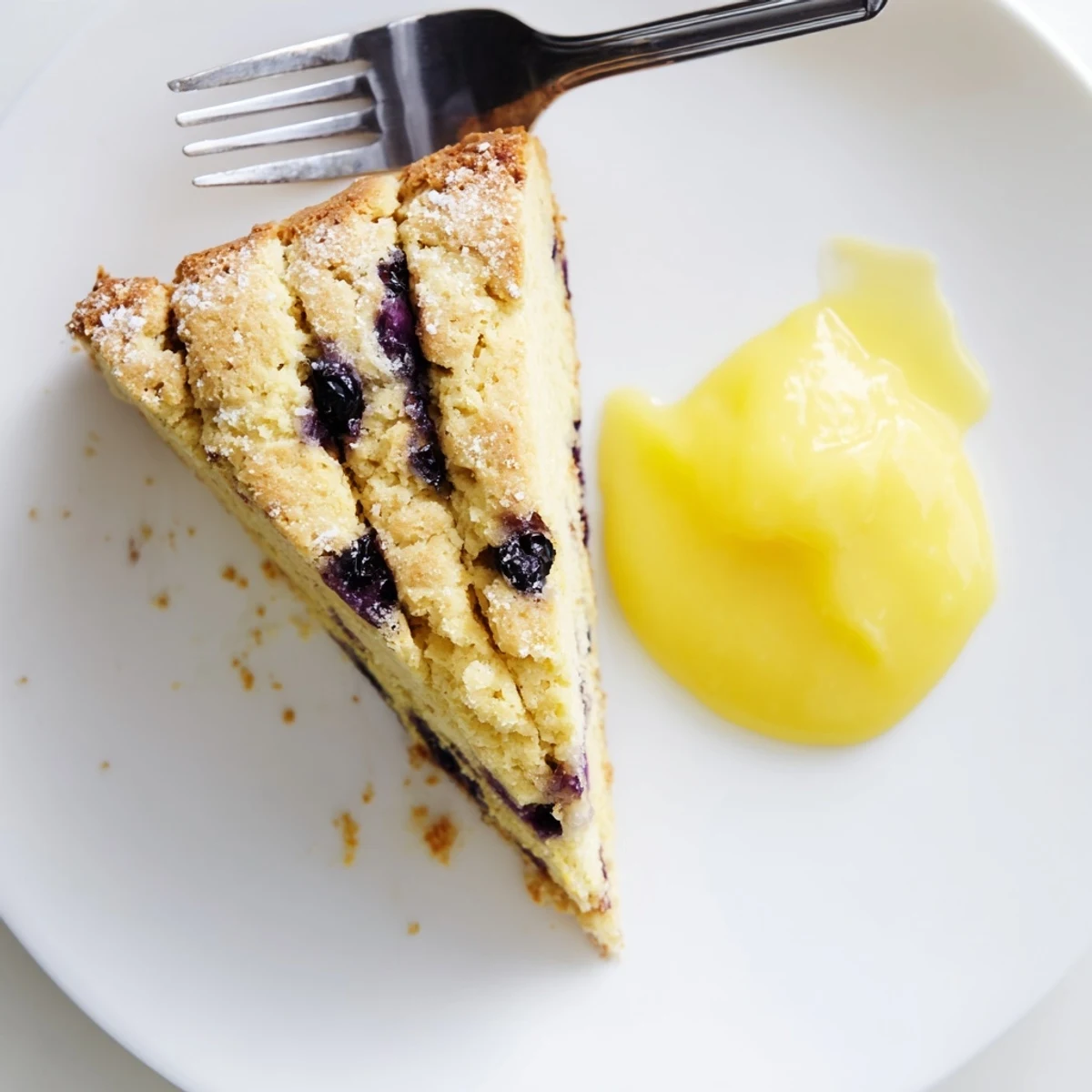 A close-up of Lemon Blueberry Scones with Lemon Curd reveals juicy berries and a flaky, buttery texture perfect for brunch.