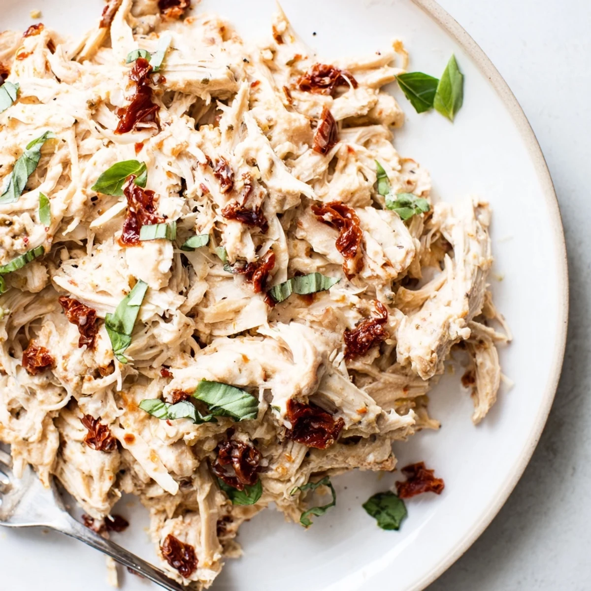 Tender, shredded Marry Me High Protein Crockpot Chicken served over cauliflower rice with fresh basil.
