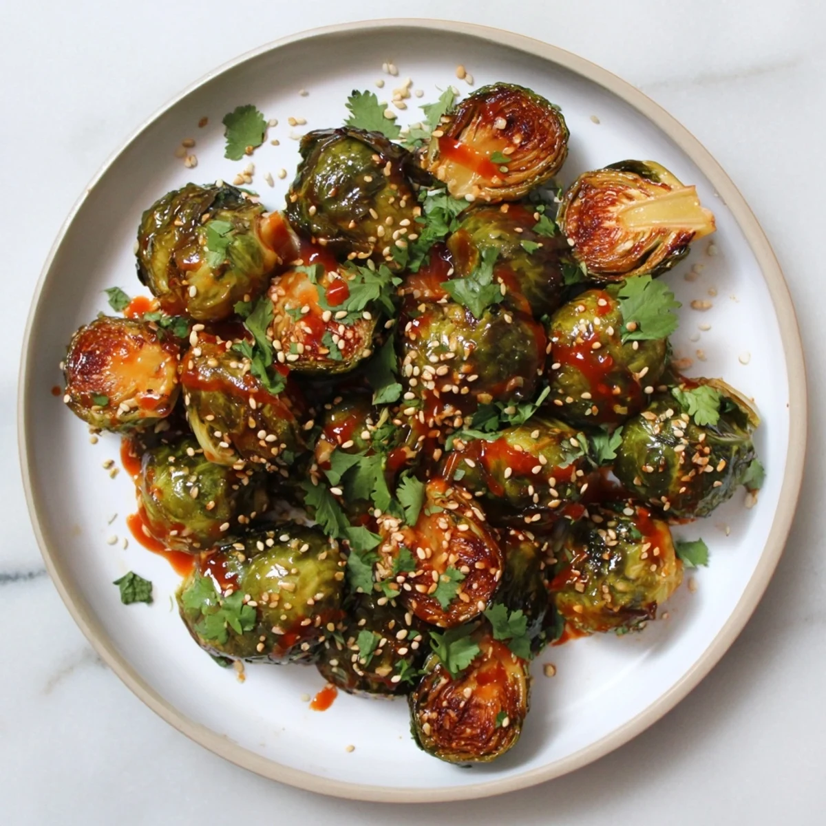 Crispy Honey Sriracha Brussels Sprouts garnished with sesame seeds on a plate.
