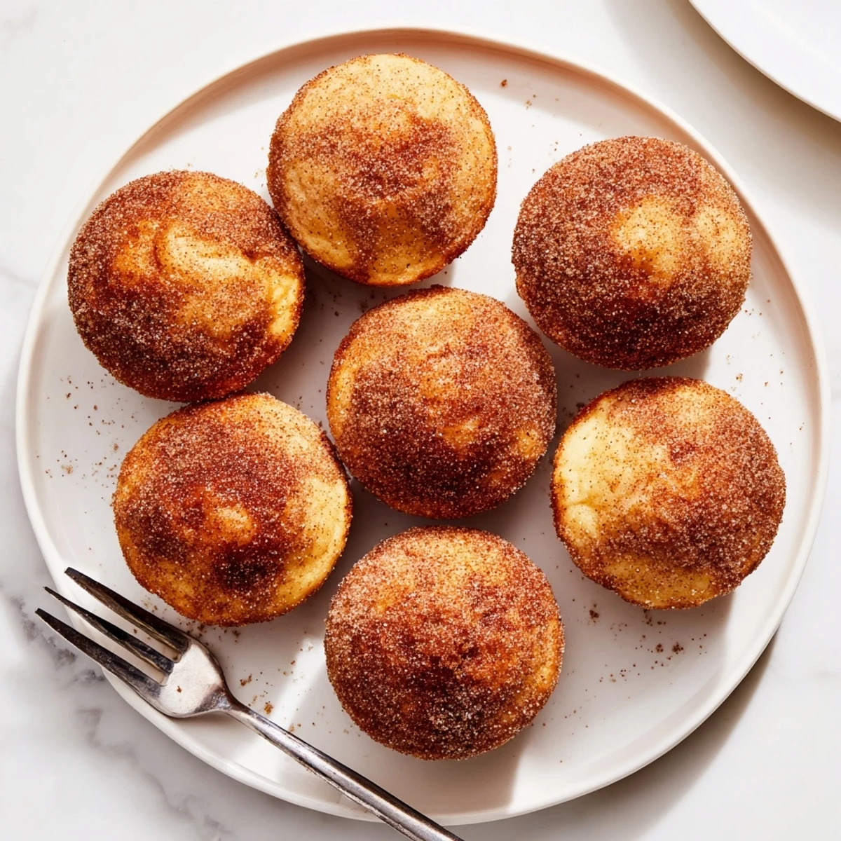 Freshly baked Cinnamon Sugar French Toast Muffins arranged in a white ceramic muffin tin, ready for a cozy brunch serving suggestion.