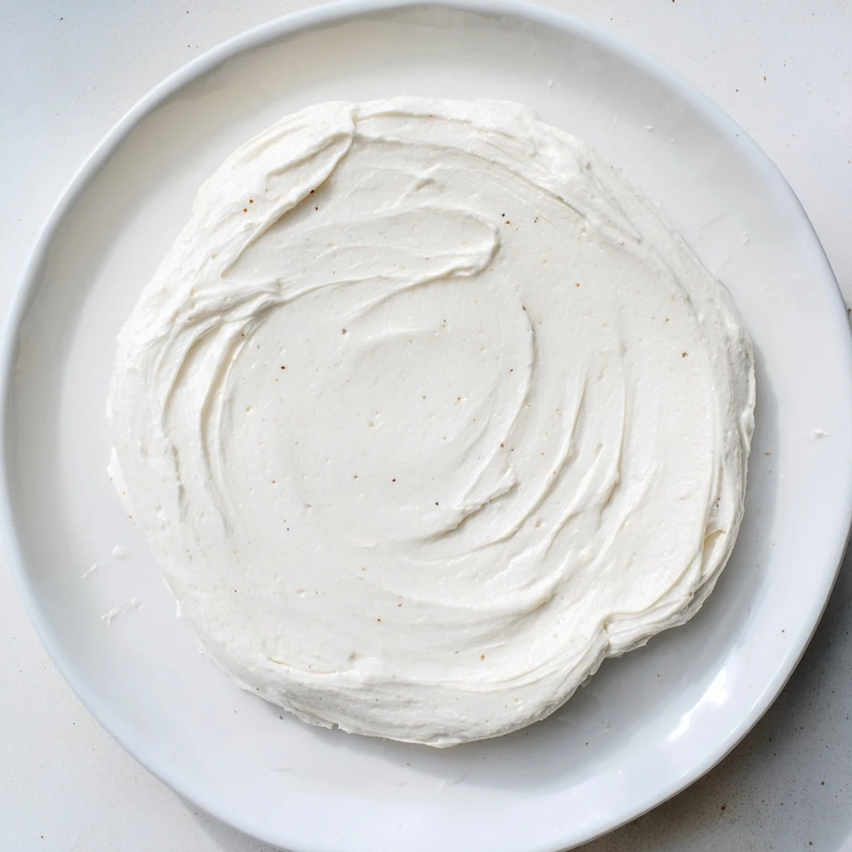 Easy Sugar Cookie Frosting with a soft crust, drizzled over warm sugar cookies on a plate.