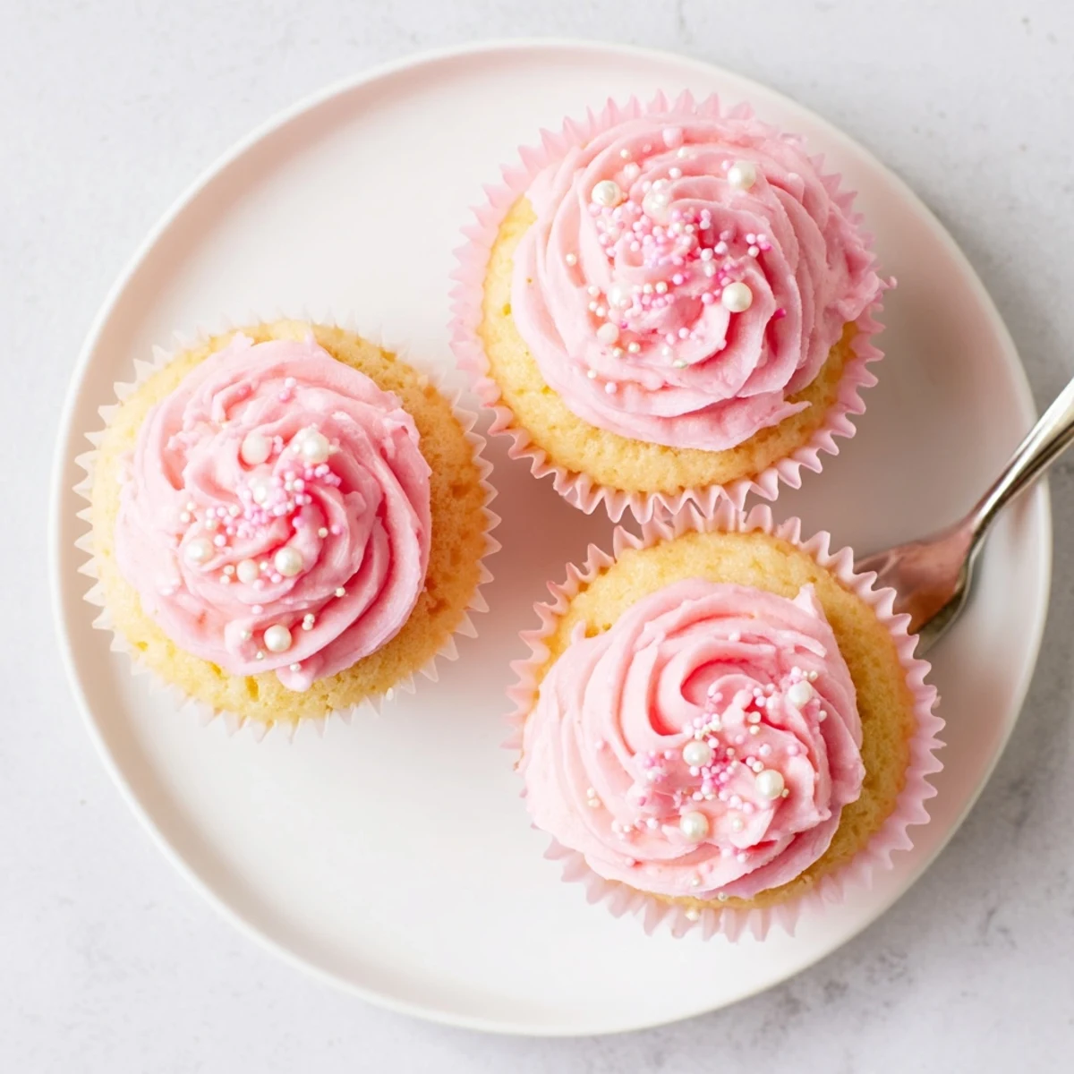 Four tender Girl Baby Shower Cupcakes topped with fluffy pink buttercream and edible pearls sit ready for a celebration.  