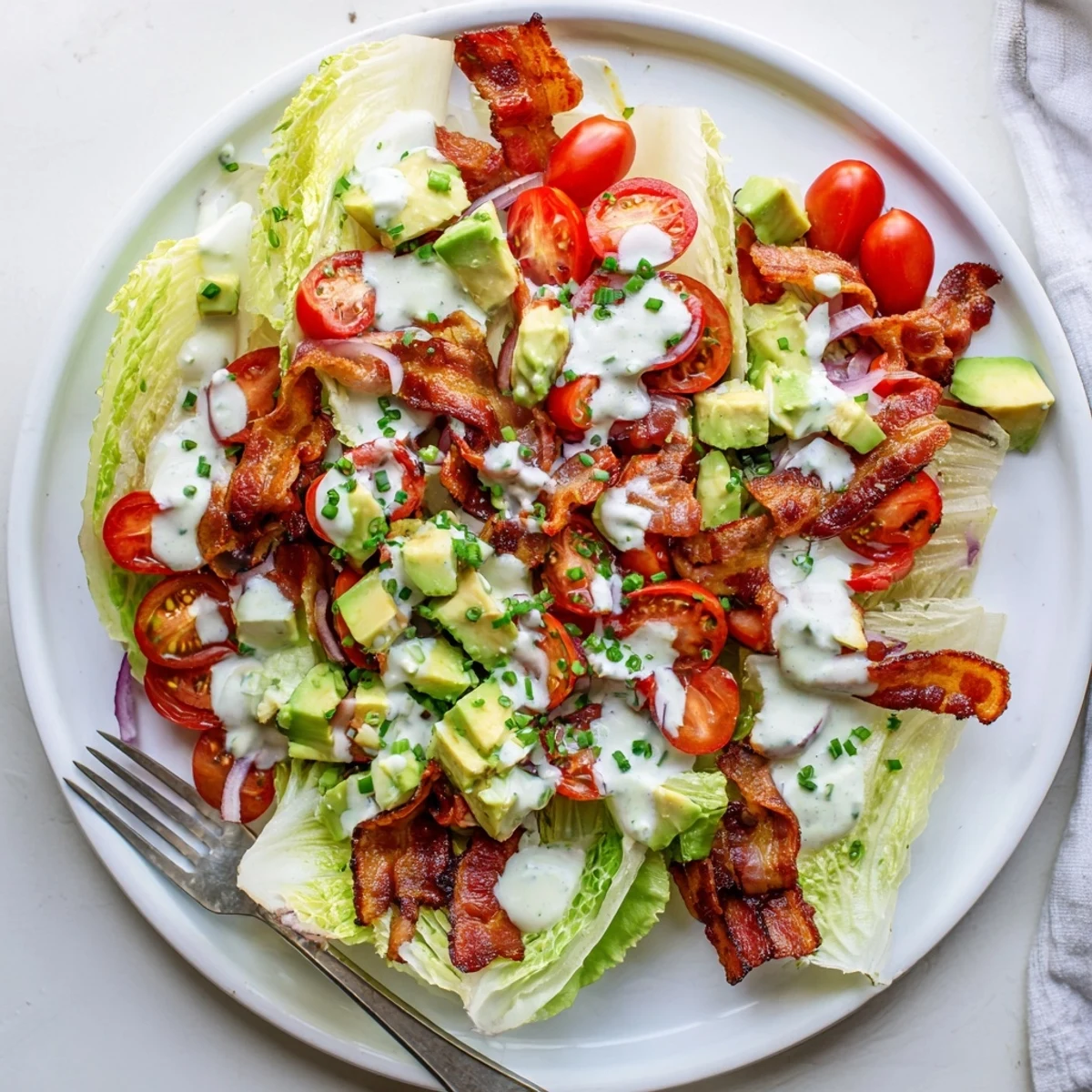 Crispy Bacon Keto BLT Salad in a white bowl, with fresh romaine, cherry tomatoes, and avocado slices.
