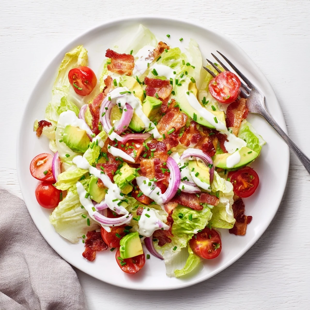A close-up of Crispy Bacon Keto BLT Salad showing crumbled bacon, red onion, and creamy keto dressing drizzled.