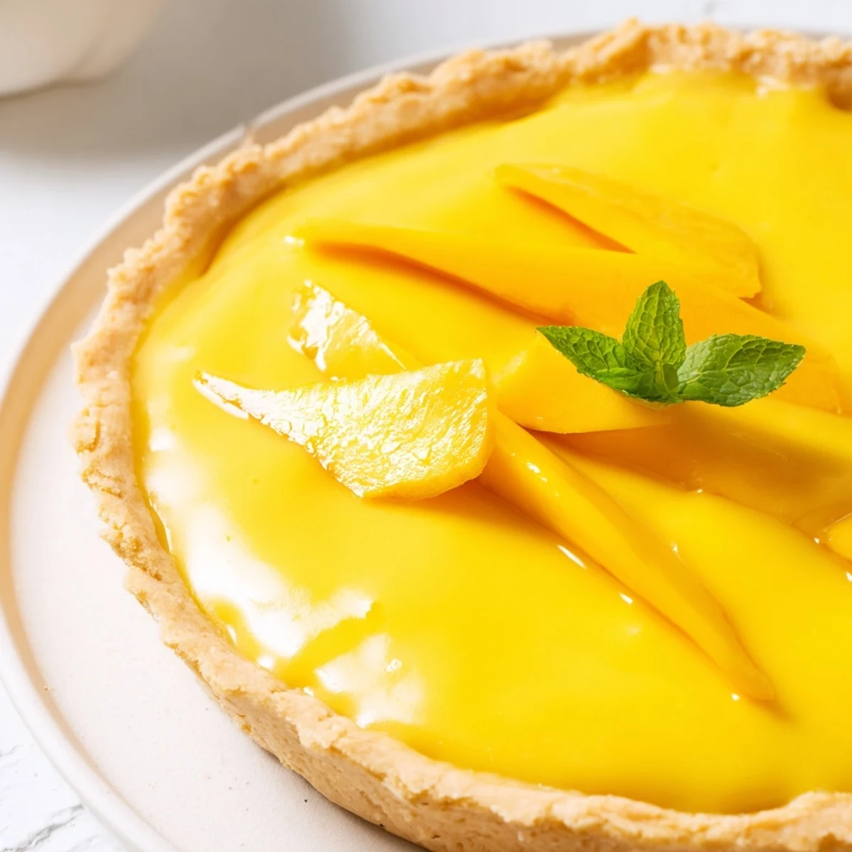 Silky mango curd tart in crisp pastry topped with vibrant fruit for summer dessert