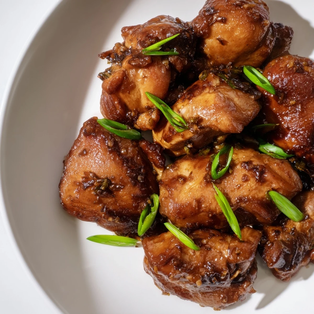 Tender browned chicken simmering in sticky sweet savory Mongolian sauce with fresh green onion garnish
