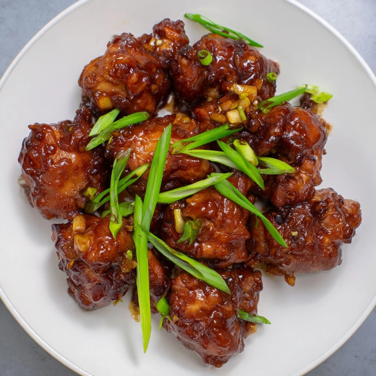 Golden glazed sweet savory Mongolian chicken pieces coated in thick caramelized soy ginger sauce