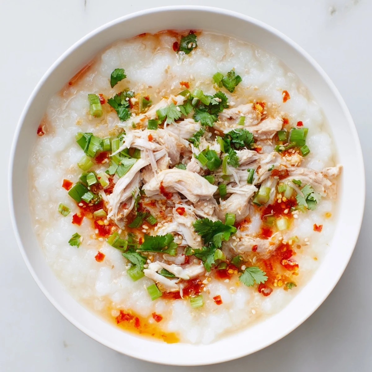 Creamy leftover Thanksgiving turkey congee garnished with fresh scallions, cilantro, and crispy shallots