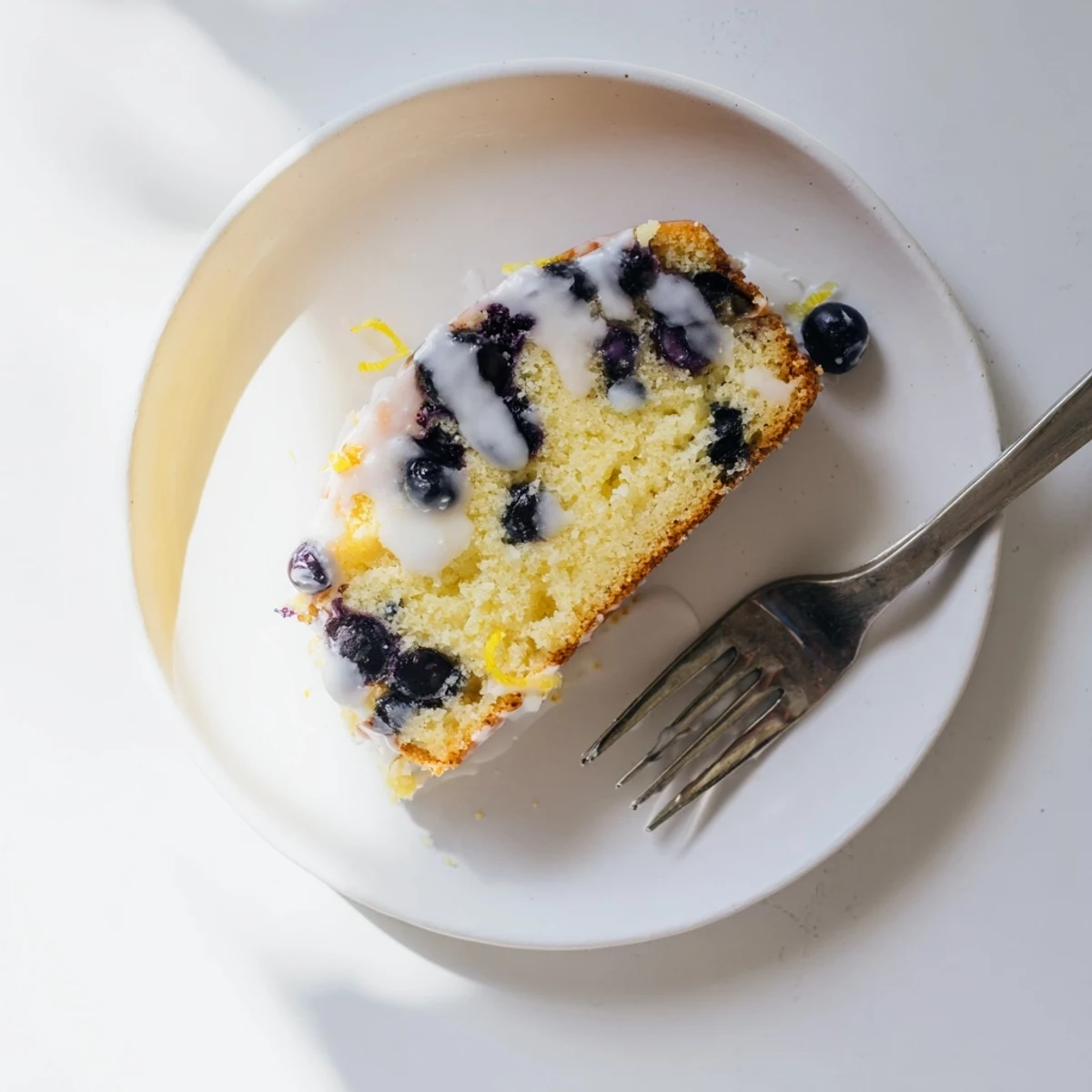 Golden lemon blueberry cake drizzled with tangy white glaze on a serving platter