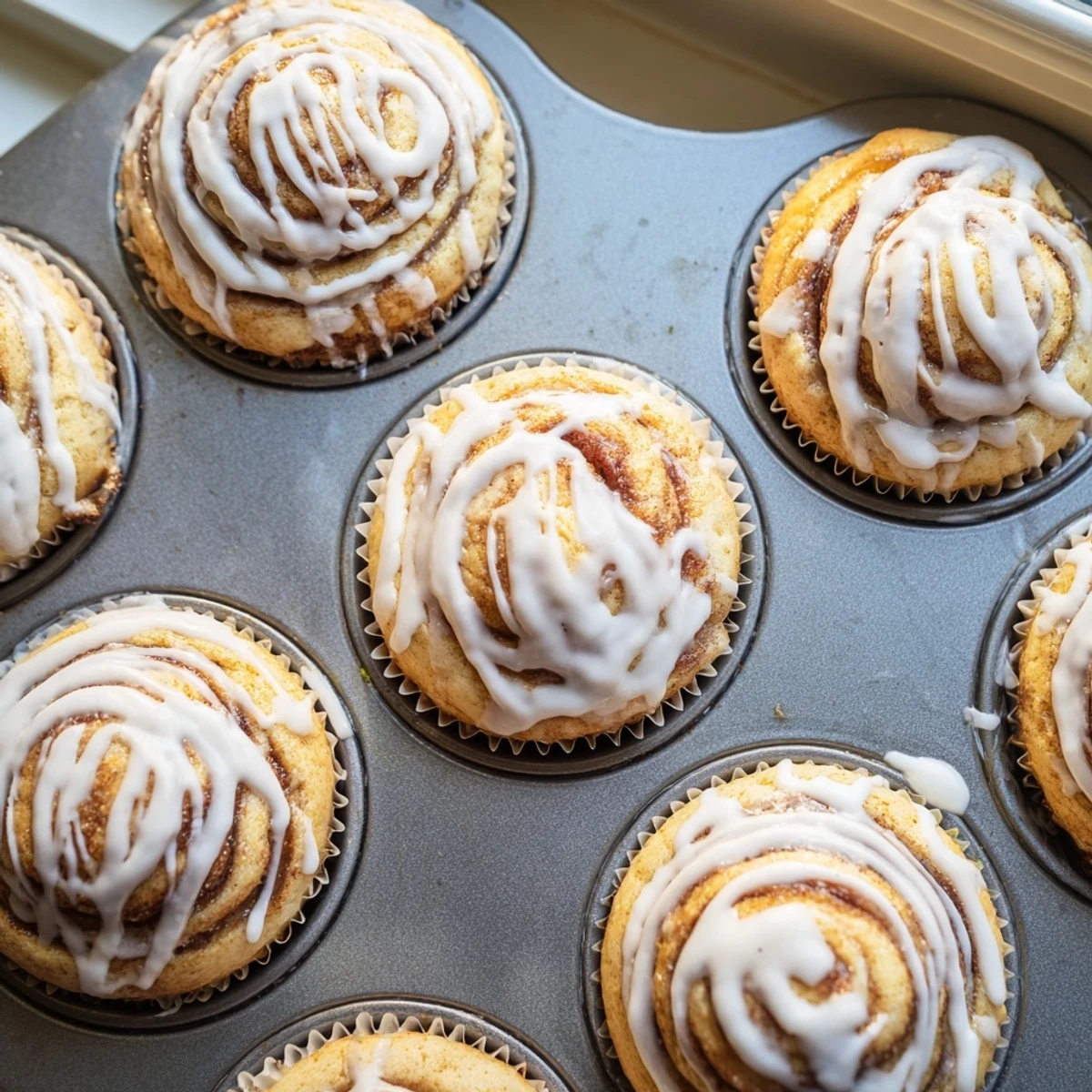Freshly baked cinnamon roll protein muffins with golden tops and sweet cinnamon swirls