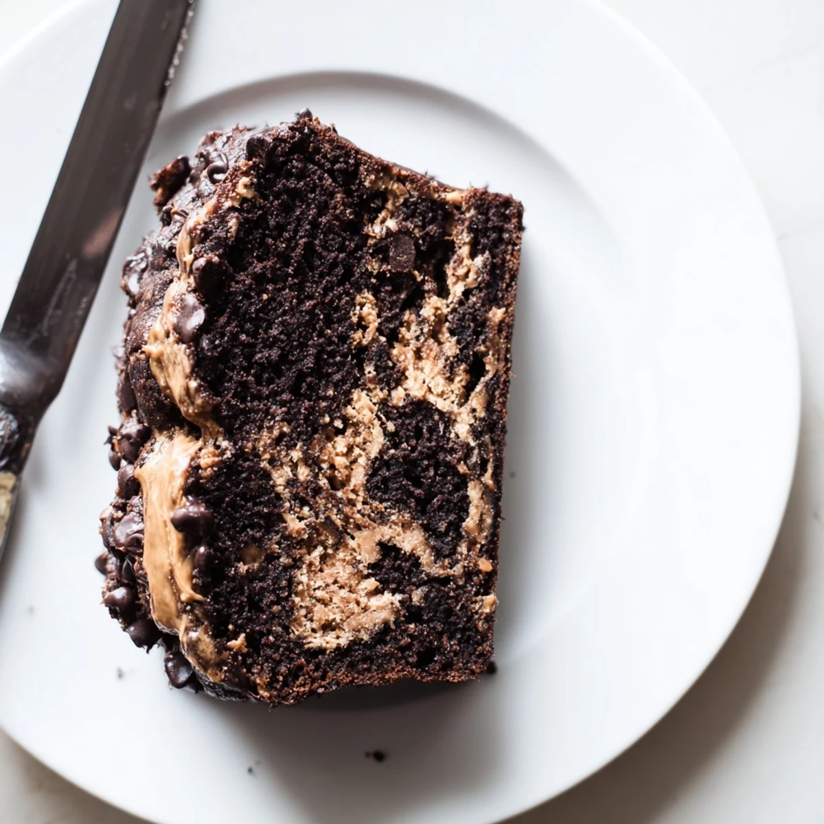 Chocolate peanut butter banana bread loaf with peanut butter swirl and chocolate chips on a wooden cutting board