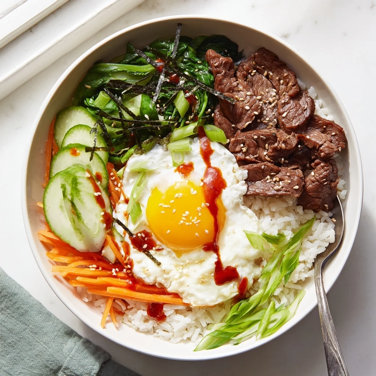 Vibrant bowl topped with runny egg gochujang drizzle and arranged vegetables surrounding tender beef on warm white rice