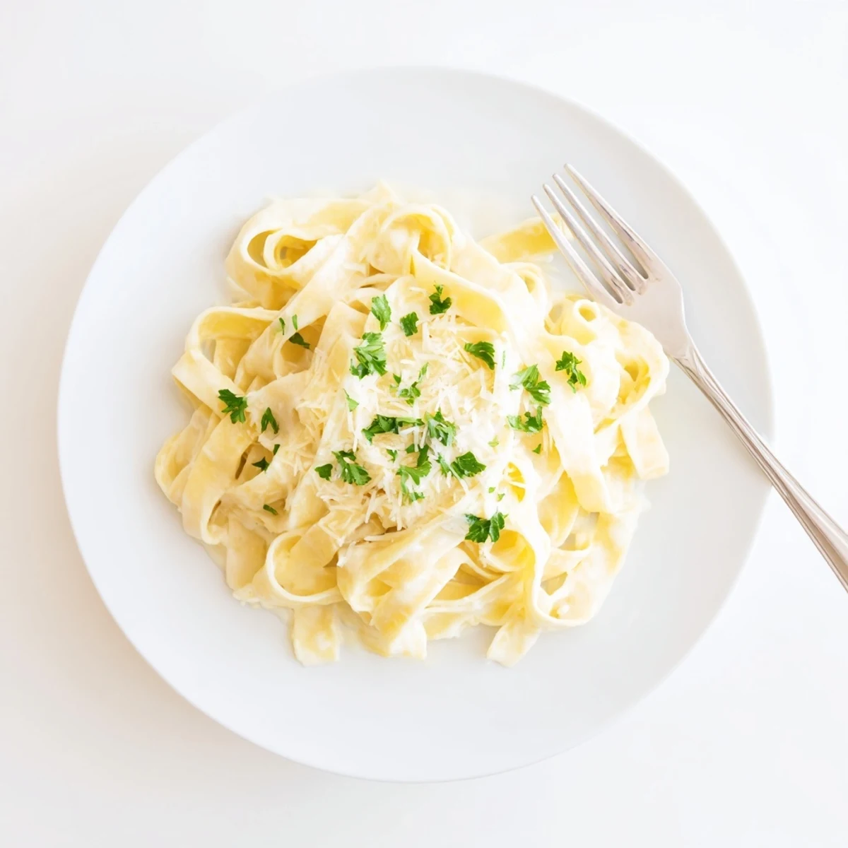 Golden fettuccine noodles coated in a velvety white Parmesan sauce with fresh parsley garnish