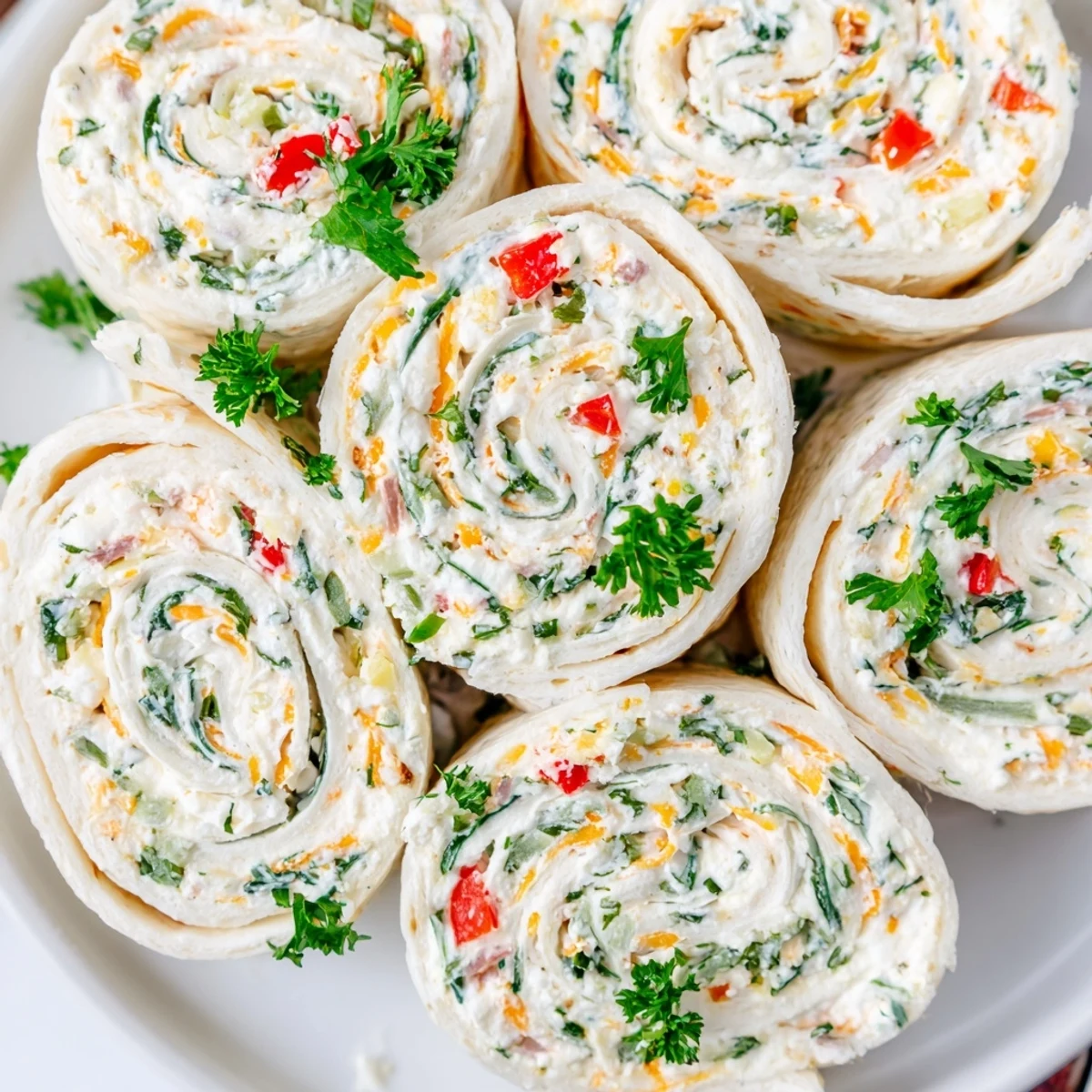Party-ready cream cheese pinwheels arranged on serving platter with vibrant red and green filling visible