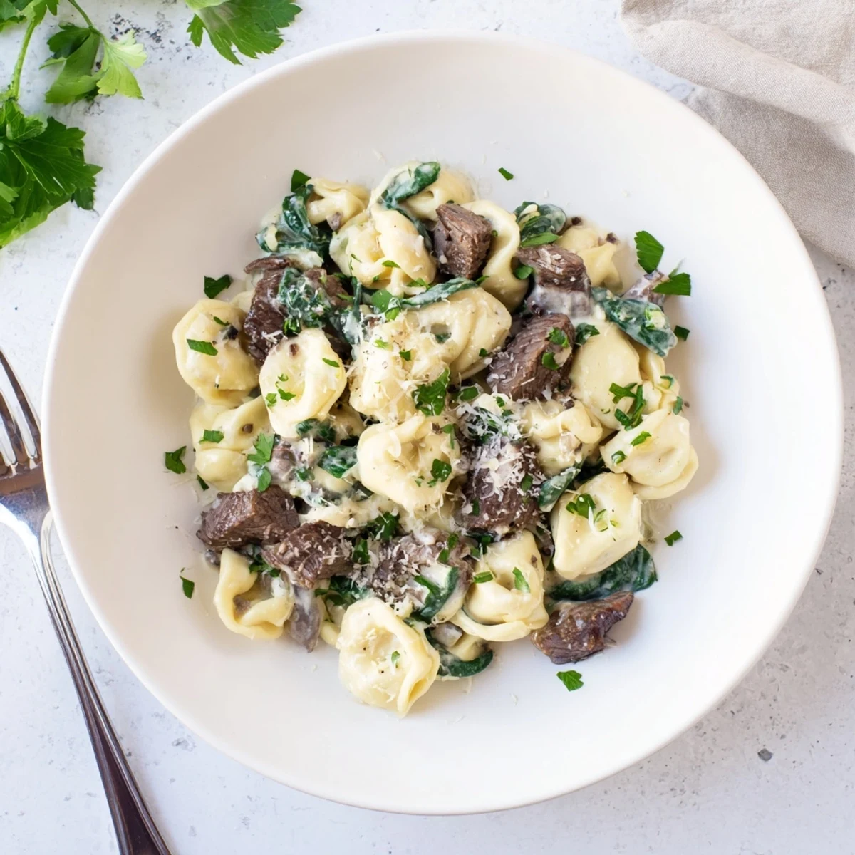 Golden garlic steak tortellini tossed in rich cream sauce with fresh spinach and Parmesan
