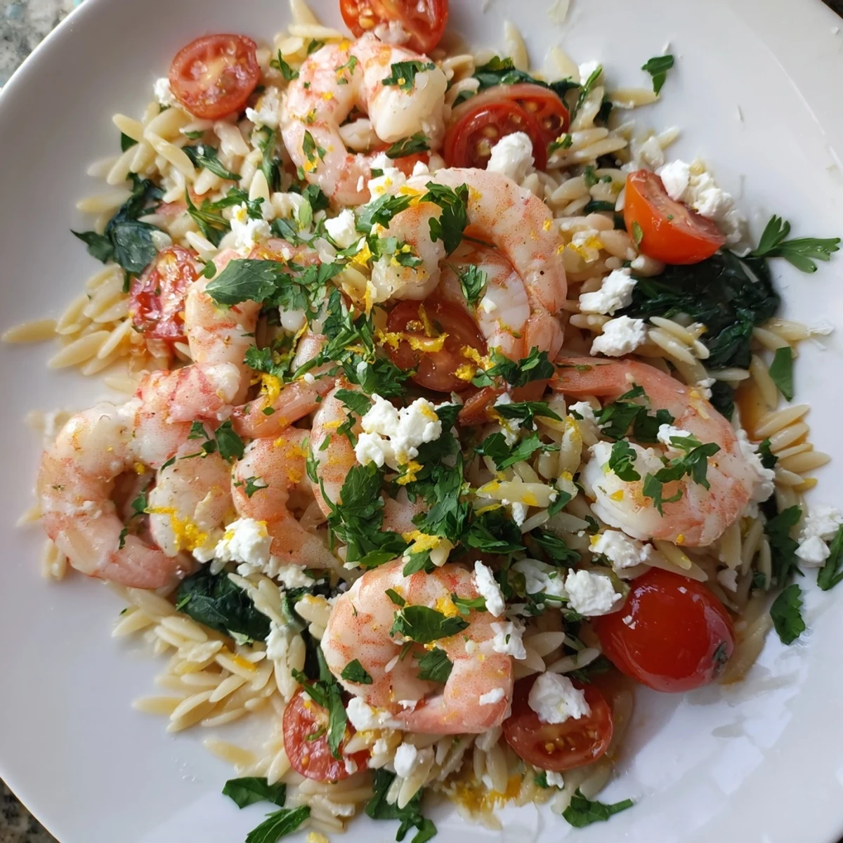 Creamy lemon feta orzo with plump pink shrimp wilted spinach and bright cherry tomatoes