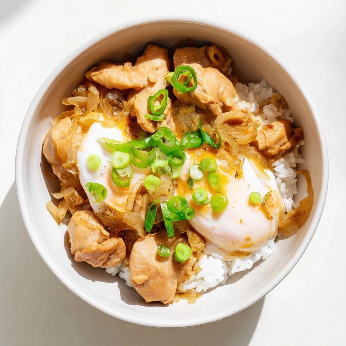 Homemade Oyakodon served in a white bowl garnished with fresh sliced spring onions