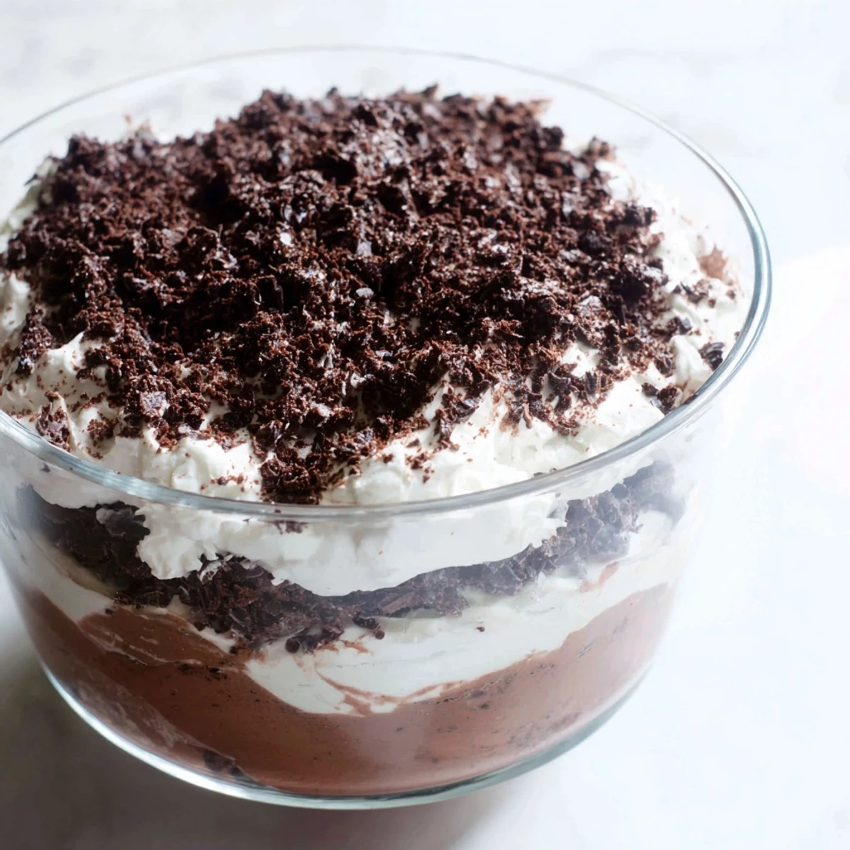 Glass trifle bowl displaying layered keto dirt cake with chocolate crumbs and creamy pudding