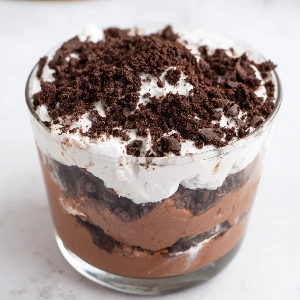 Sliced square of keto dirt cake revealing whipped cream and pudding layers beneath chocolate soil