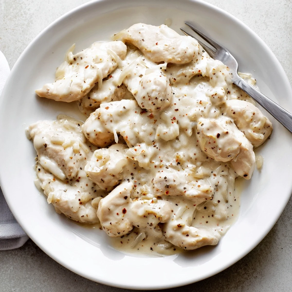 Golden brown Crockpot chicken thighs swimming in a rich creamy white gravy sauce