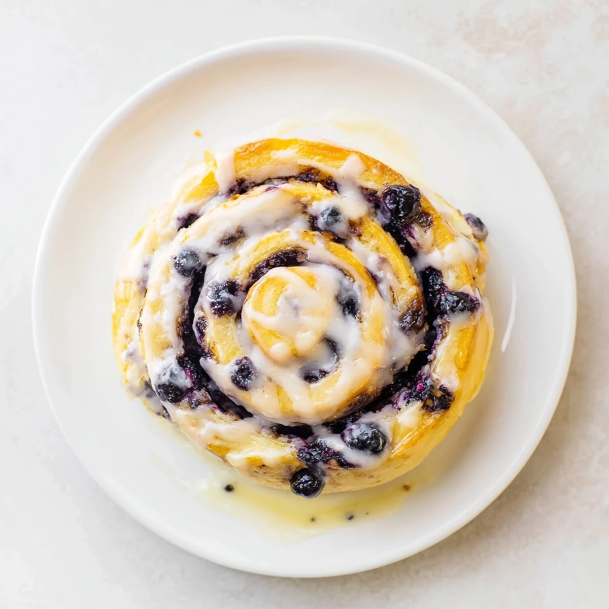 Golden lemon blueberry rolls drizzled with white lemon glaze on a rustic wooden board