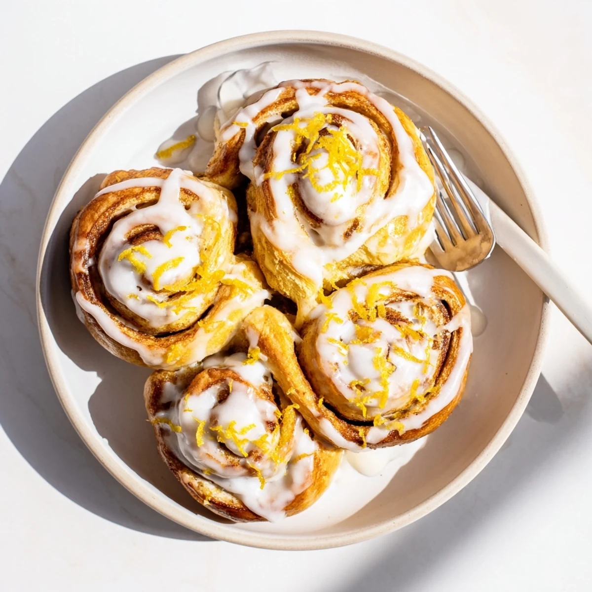 Freshly baked lemon rolls topped with glossy icing and extra lemon zest for breakfast