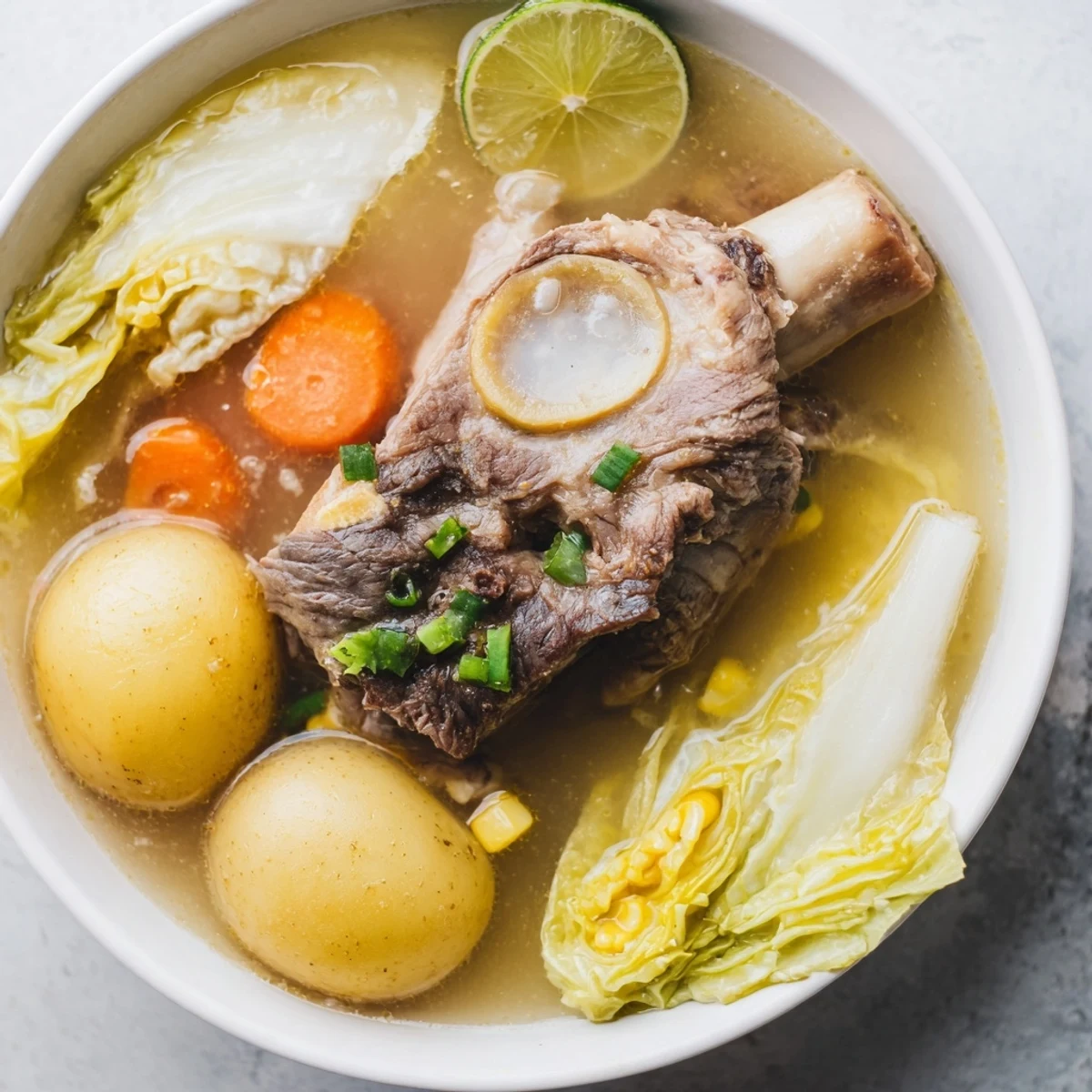 Steaming bowl of Filipino Bulalo Beef Shank Soup with golden broth and tender vegetables