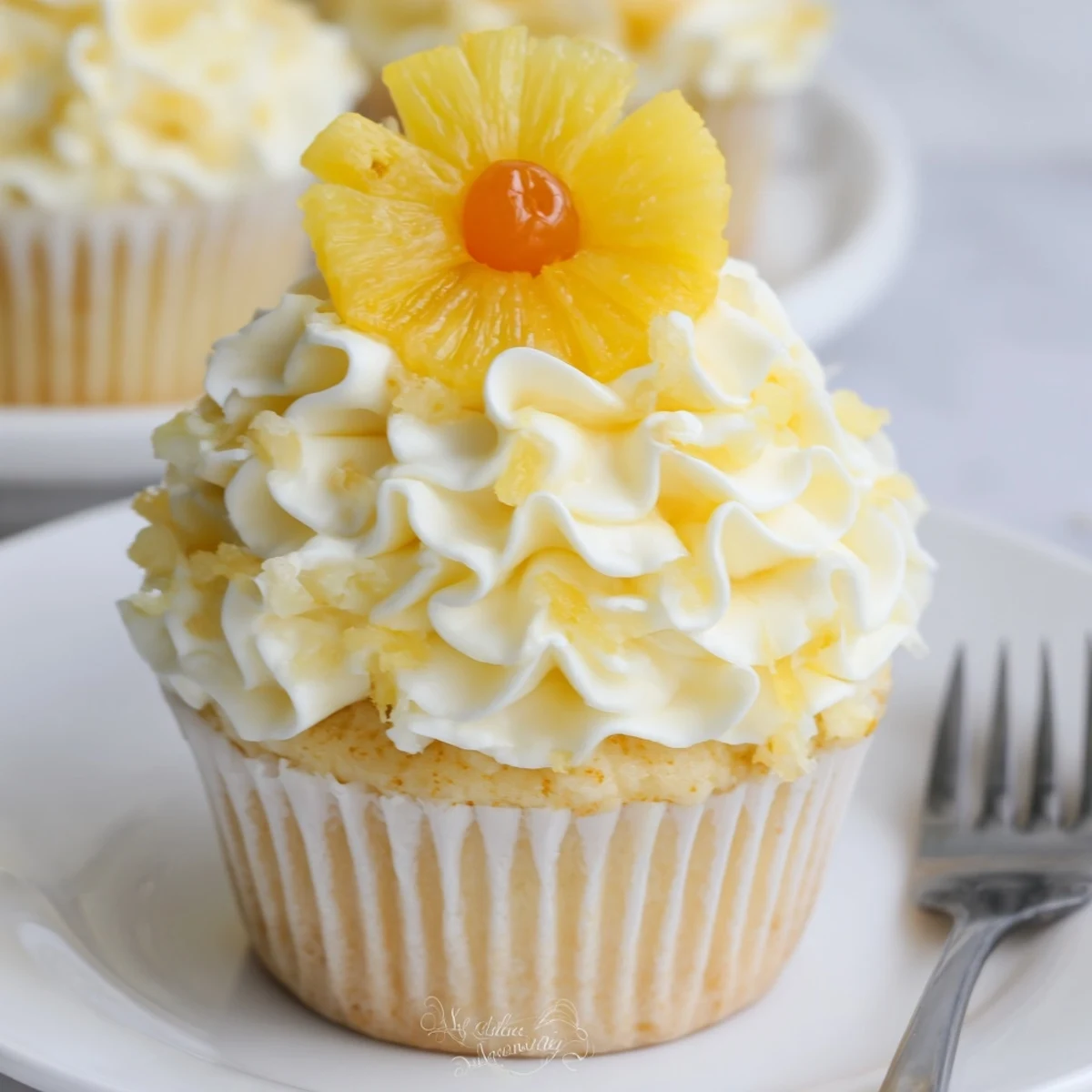 Plate of Dole Whip Cupcakes Recipe garnished with dried pineapple flowers and cherries