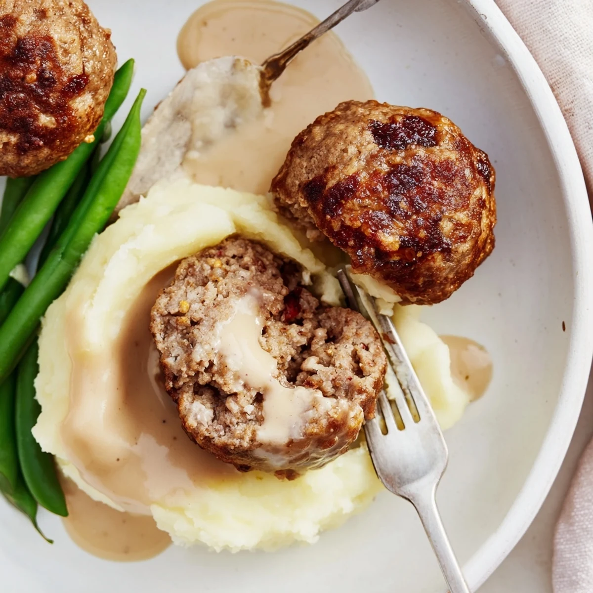 Skillet with Homemade Ikea Meatballs simmering in rich cream sauce, aromatic spices