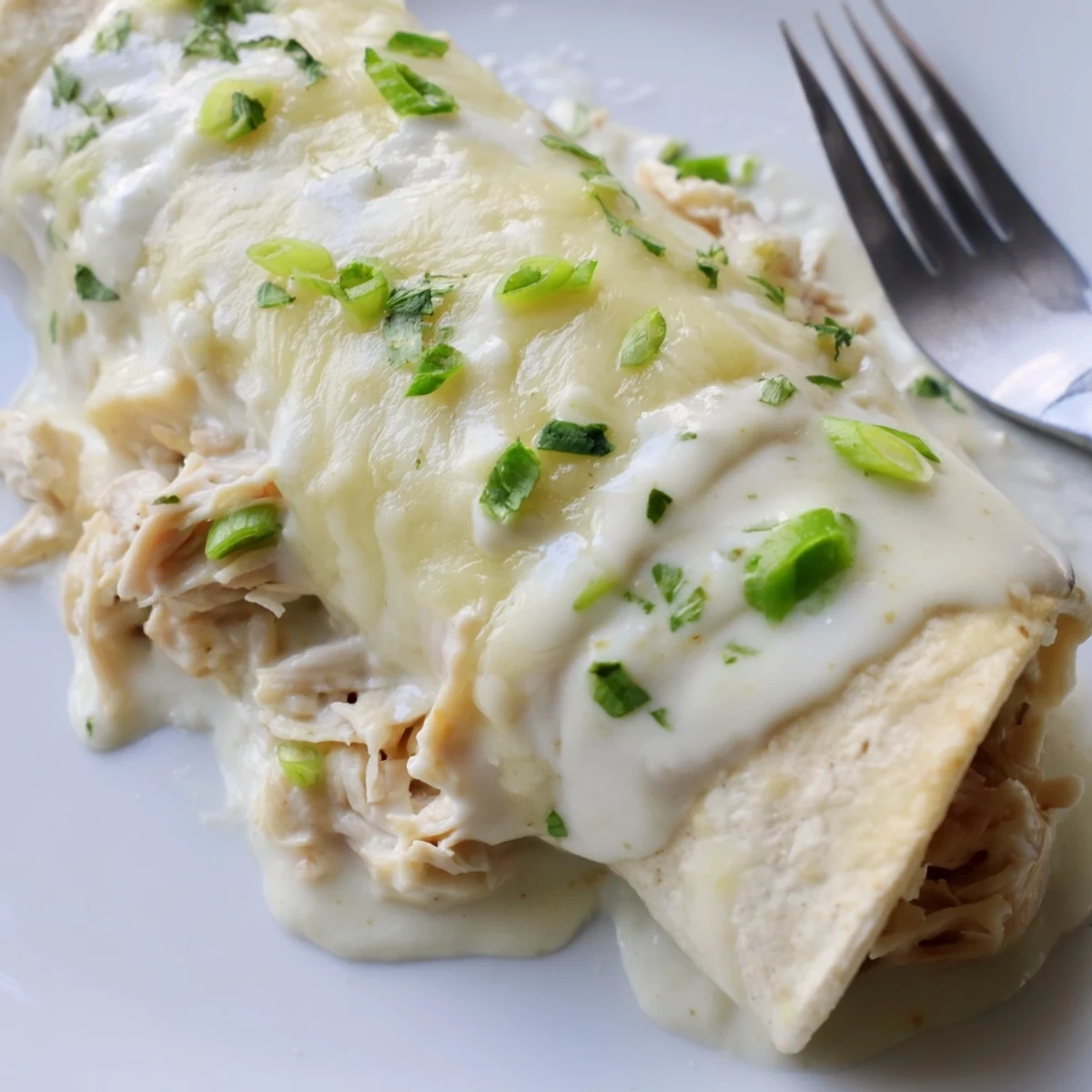 Creamy White Chicken Enchiladas cut open, tender shredded chicken and melted cheese.