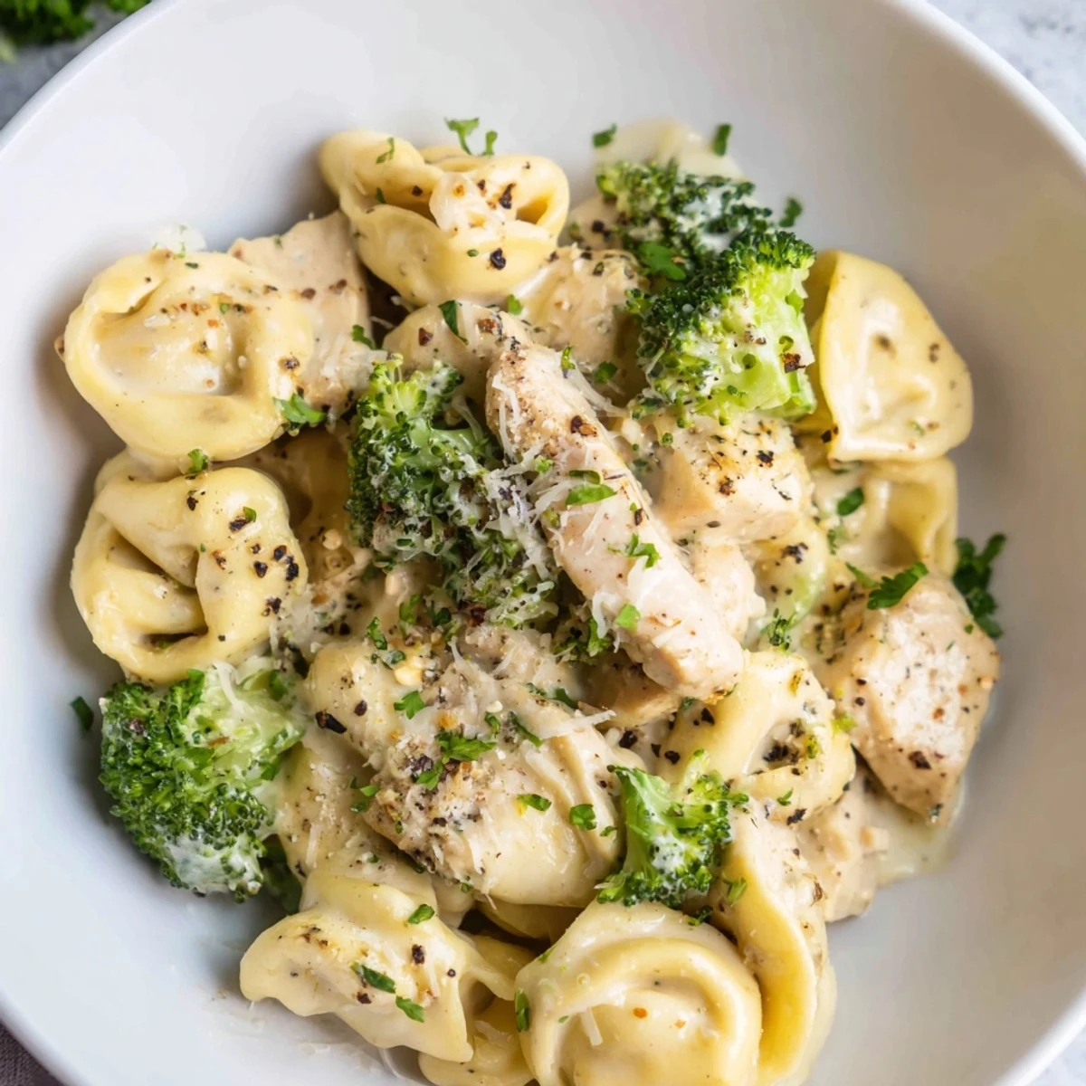 Creamy Garlic Parmesan Tortellini Chicken Broccoli Recipe steaming on plate, tender chicken, saucy pasta