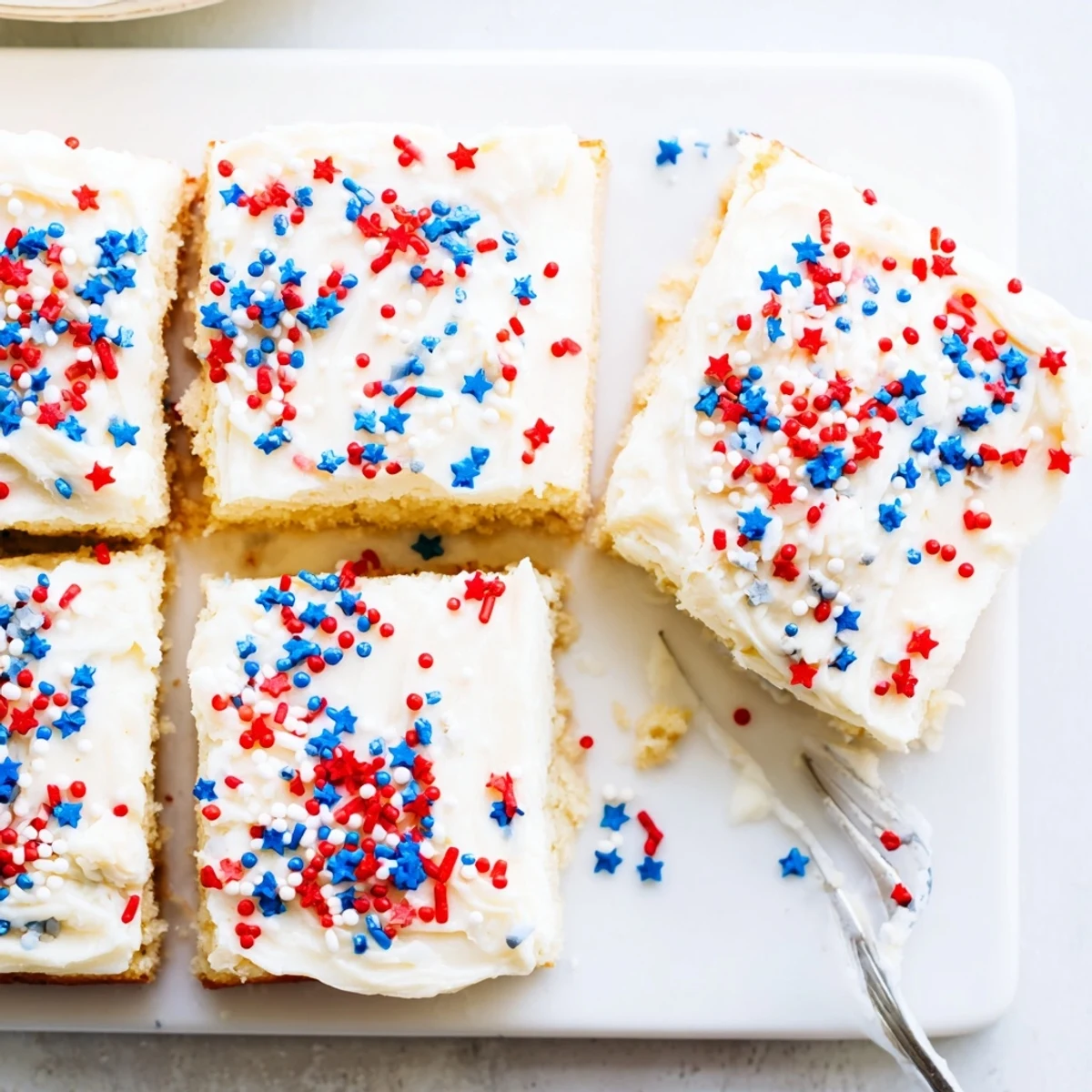 Soft baked sugar cookie bars topped with creamy vanilla frosting and festive red white blue sprinkles