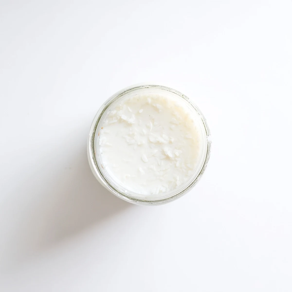 Fresh coconut milk being poured from blender into glass container, rich and dairy-free