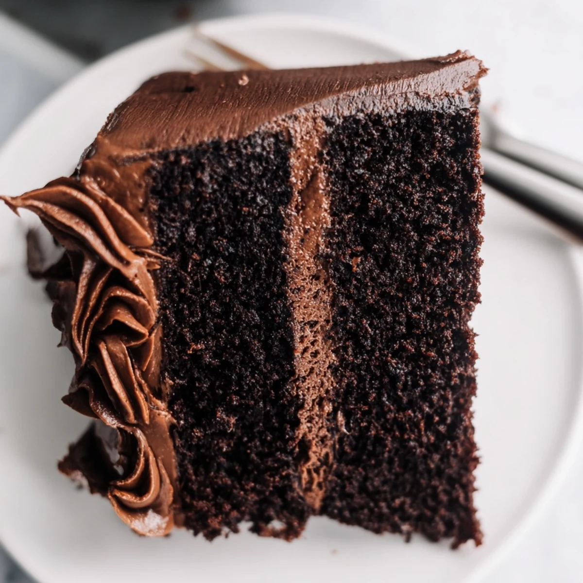 Two-layer Matilda chocolate cake topped with velvety buttercream frosting on a white serving plate