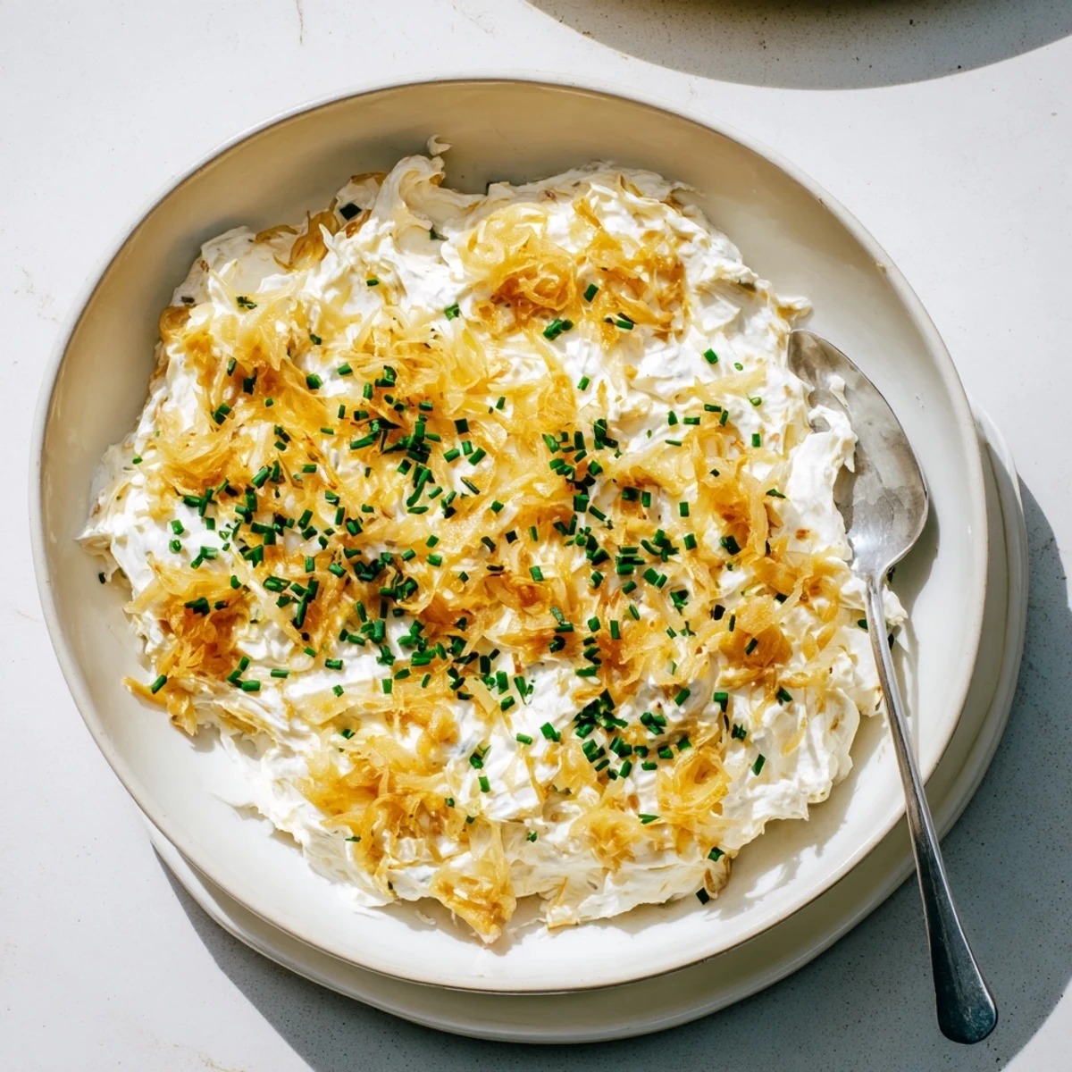 Rich homemade French onion dip served with crispy potato chips and vegetable crudités on a wooden board