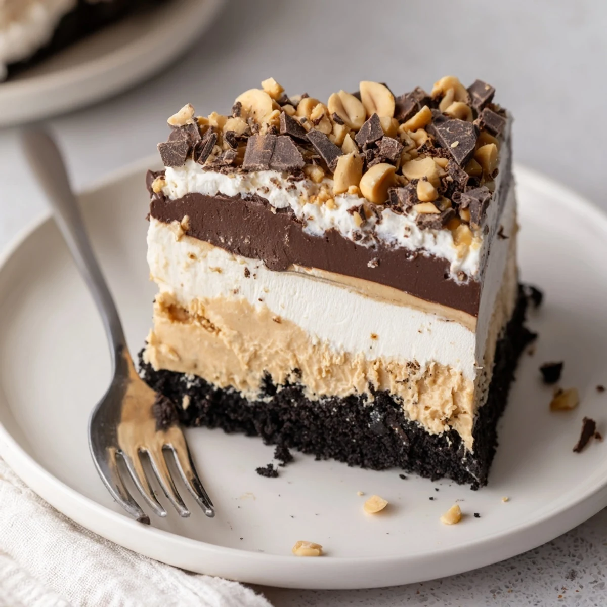 Velvety peanut butter layered delight in a glass pan dusted with chocolate shavings