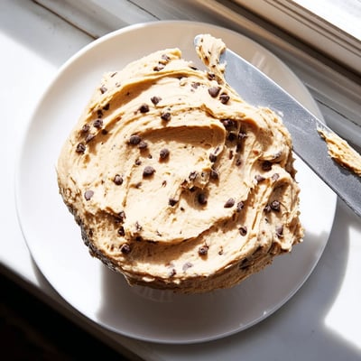 Close-up of Cookie Dough Frosting swirled over a rich chocolate cake, highlighting its soft texture and edible cookie dough flavor.  