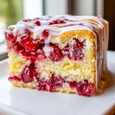 A close view of Easy Cherry Pie Bars with bubbly red filling and powdered sugar glaze.