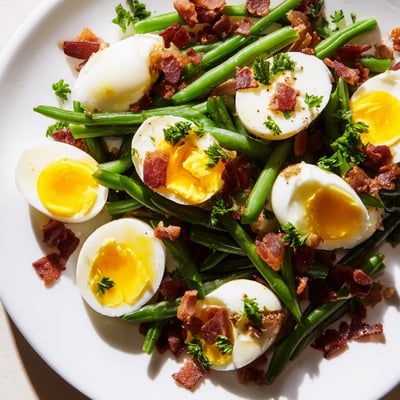 Vibrant fresh produce and smoky bacon create a hearty lunch salad; the Green Bean, Bacon, and Egg Salad is plated with parsley.