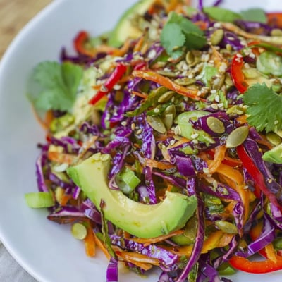 A close-up of Avocado Cabbage Salad topped with toasted pumpkin seeds, ready for a light lunch or side.