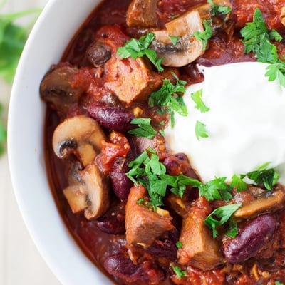 Spiced Chilli Mushroom Con Carne simmering in a pot with diced tomatoes and kidney beans.