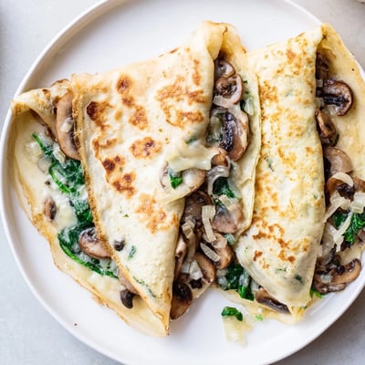 Thin French savory crepes rolled around tender spinach and golden mushrooms with gooey melted cheese