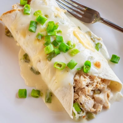 Creamy White Chicken Enchiladas served family style with cilantro and warm tortillas.