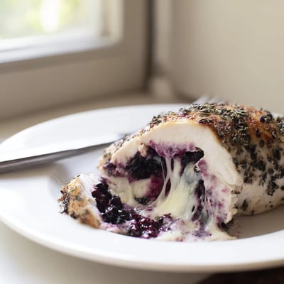 Golden baked blackberry jalapeno stuffed chicken cut open to reveal a melty sweet and spicy center